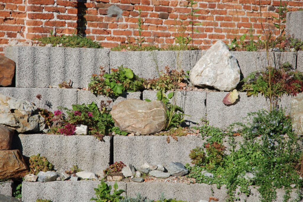 Tiered concrete block wall holding a planted garden bed, similar to a low seating wall in Chicago-area hardscaping