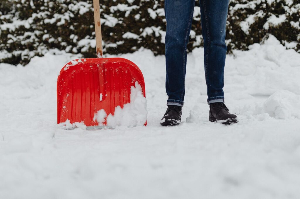 Homeowner clearing snow with a plastic shovel at a Chicago-area home, safe for artificial turf systems