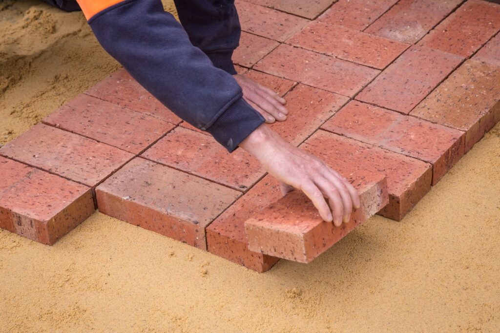 Brick pavers being reset into fresh bedding sand during an R&G Almanza patio re-leveling repair